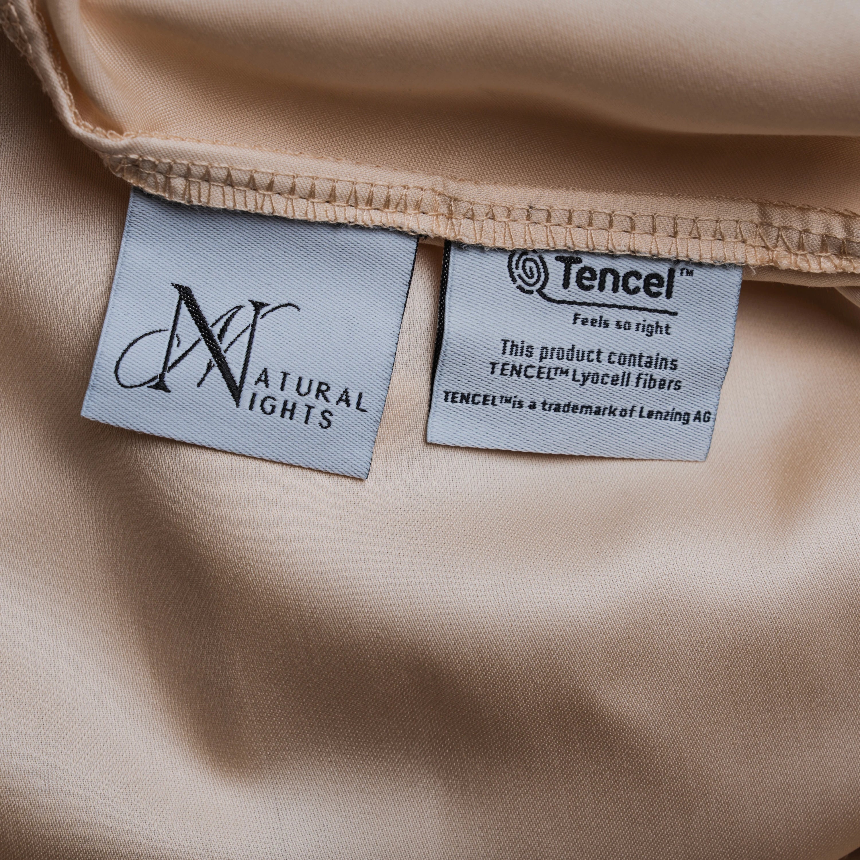 Beiges Spannbettlaken aus Micro TENCEL™ Lyocell „Shell Dune“ mit Natural Nights- und TENCEL™-Label, Detailaufnahme der Etiketten auf seidigem Stoff