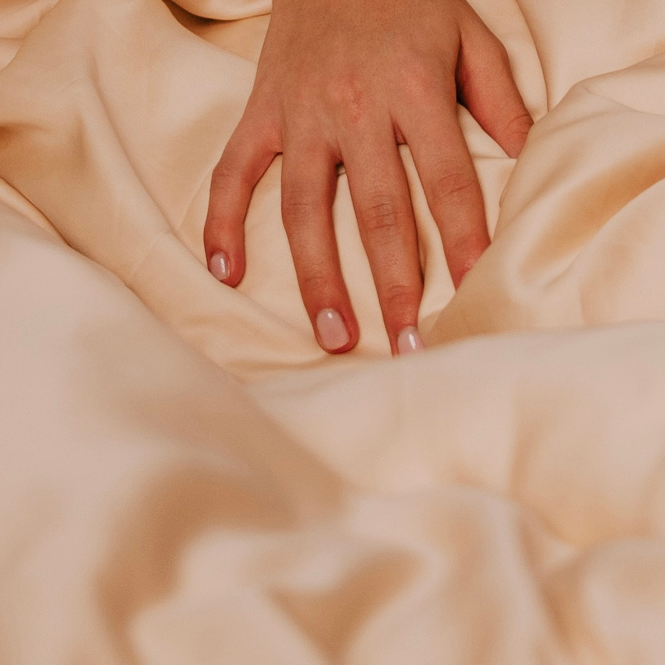 Hand berührt sanft glatte Lyocell-Bettwäsche – Symbolbild für hautfreundliche, reizfreie Materialien bei empfindlicher Haut.