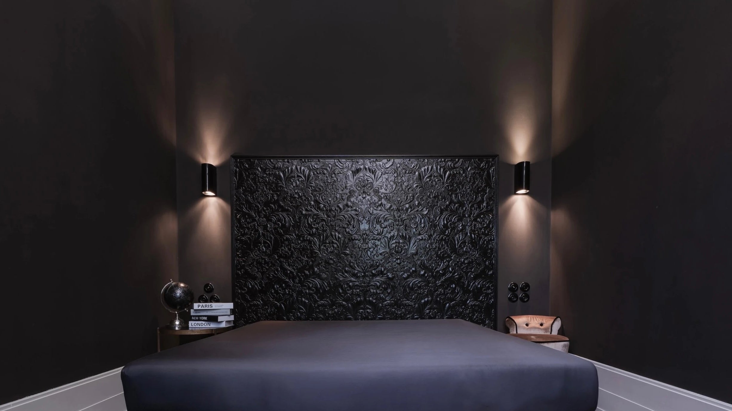 Graues Natural Nights Spannbettlaken aus nachhaltigem TENCEL™ Lyocell in einem modernen Schlafzimmer mit schwarzer Akzentwand, stilvoller Beleuchtung und eleganten Dekoelementen.