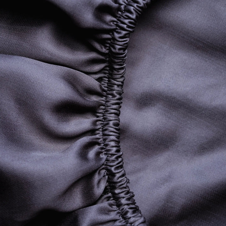 Dunkelgraues Spannbettlaken aus Micro TENCEL™ Lyocell, Nahaufnahme des Rundumgummis, seidig-glatt, atmungsaktiv und temperaturregulierend