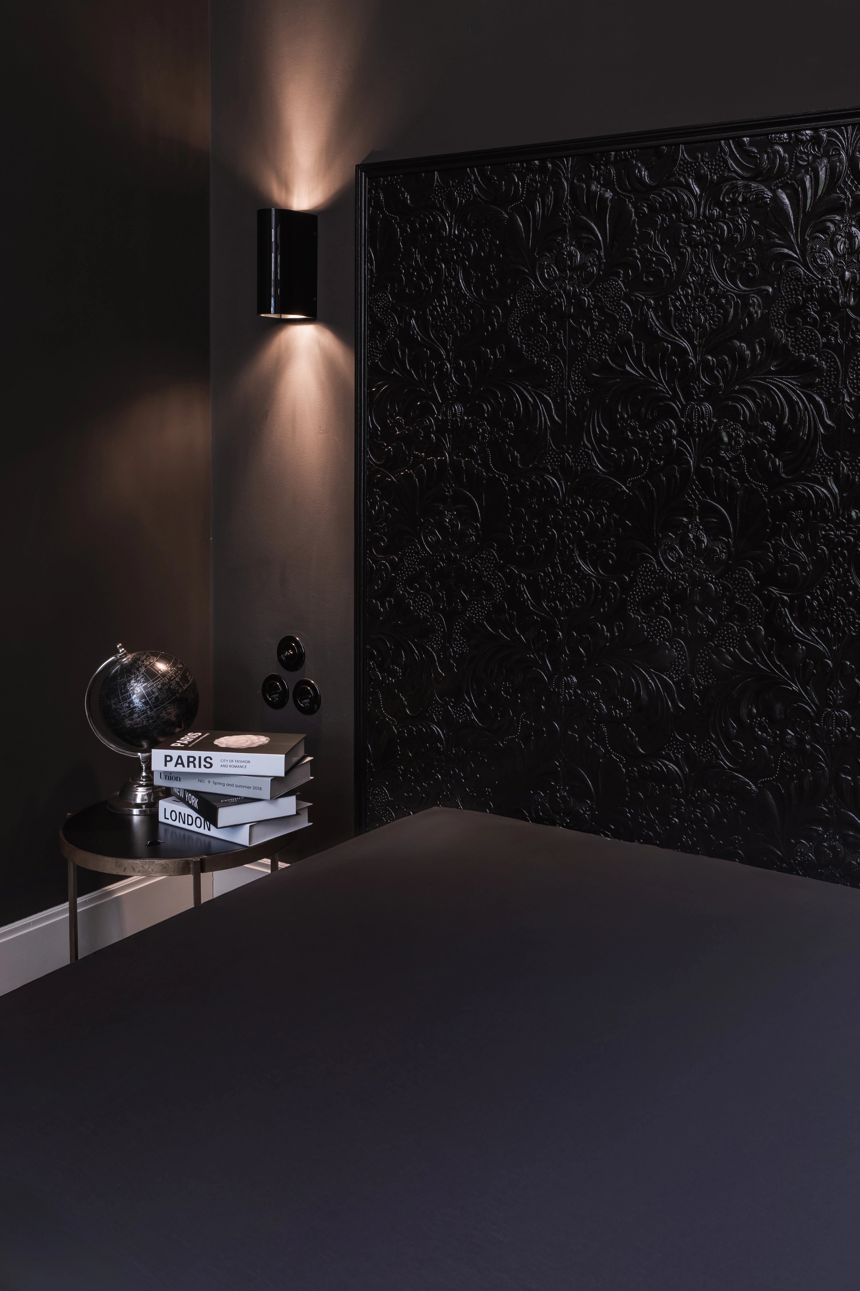 Anthrazitfarbenes Tencel-Spannbettlaken von Natural Nights in elegantem Schlafzimmer mit schwarzer, floral geprägter Akzentwand und stilvoller Beleuchtung